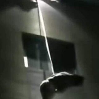 夜间，一名男子通过绳索悬在公司建筑外墙半空